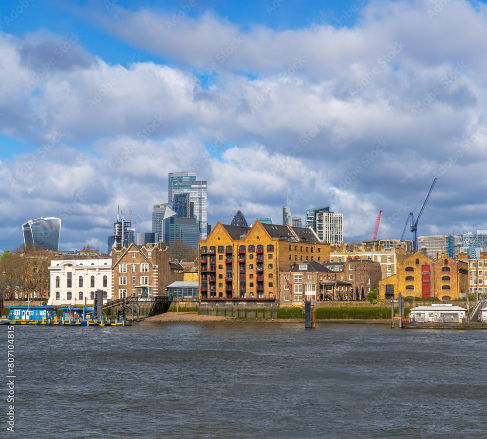 Fototapeta premium St John's Wharf residential area near the Canary Wharf district along the River Thames, formerly a storage area with traditional riverside warehouses. Skyscrapers in the background.