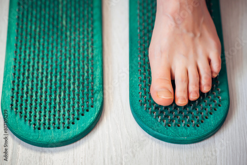 Close-up of Sadhu board with human foot. Feet standing on nails bed. Yoga exercise and spiritual meditation practice desk. Alternative medicine and treatment