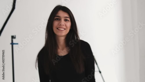 A young happy dark-haired woman is dancing in a photo studio.The woman touches her fluttering hair with her hands.