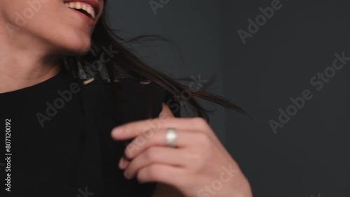 A young attractive dark-haired woman is dancing in a photo studio.The woman touches her fluttering hair with her hands,hands close-up.