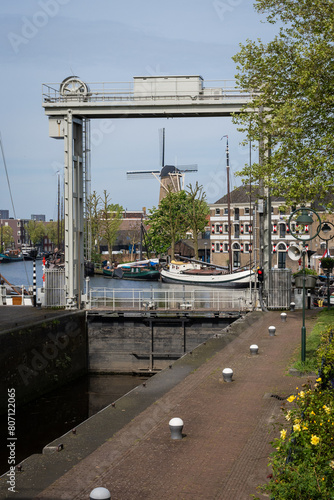 Medieval Mallegatsluis Lock  municipal monument frames rood leeuw windmill in Gouda harbour. Modern sluice gate from the late 19th century joins the river IJssel to surrounding canal  © drew