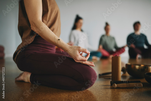 Close-up of a female yoga teacher leading a group of students through a meditation while sitting together on the floor of her studio photo