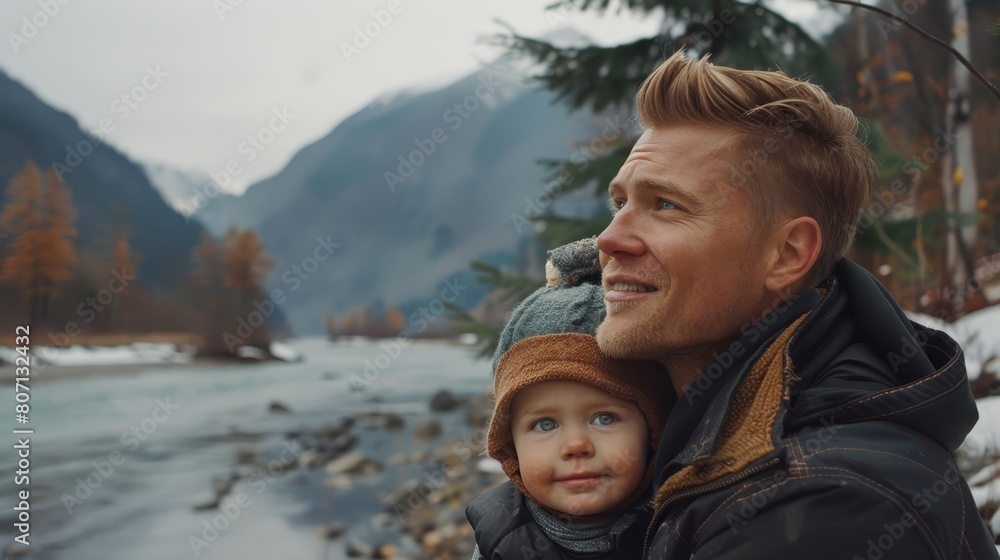 A man cradles a child against him, gazing out over a tranquil body of water Mountains and trees frame the scene in the background A man cradles a child against him, gazing out over a tranquil body of water Mountains and trees frame the scene in the background