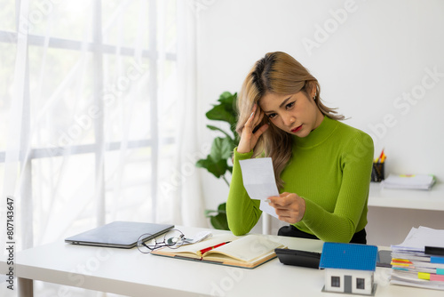 Quadro em tela A young Asian woman is worried and frustrated about her monthly expenses