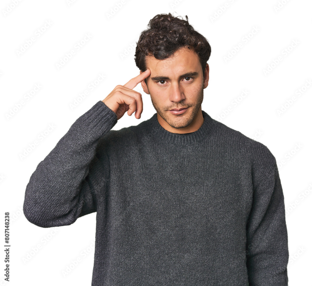 Young Hispanic man in studio pointing temple with finger, thinking, focused on a task. Young Hispanic man in studio pointing temple with finger, thinking, focused on a task.