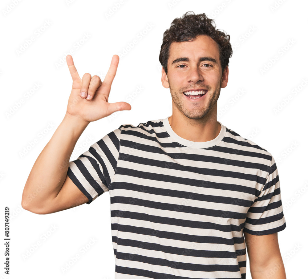 Young Hispanic man in studio showing a horns gesture as a revolution concept. Young Hispanic man in studio showing a horns gesture as a revolution concept.