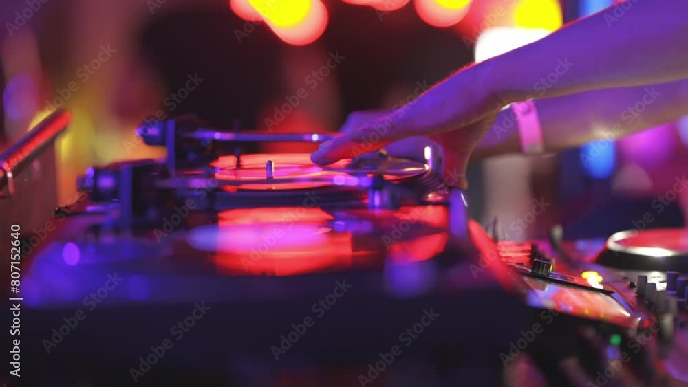 A person is playing a DJ set with a red and blue background A person is playing a DJ set with a red and blue background