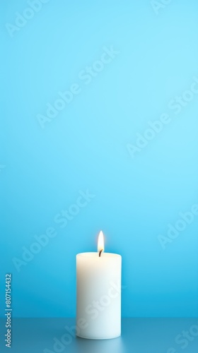 Sky Blue background with white thin wax candle with a small lit flame for funeral grief death dead sad emotion with copy space texture for display 