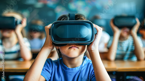 A boy wearing a blue shirt is holding a virtual reality headset. He is looking at the camera