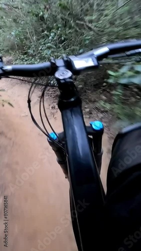 Vertical video - Point of view of Mountain male biker riding fast on flow single track trail in green forest, POV behind the bars of the cyclist. Speed riding an enduro extreme sports photo