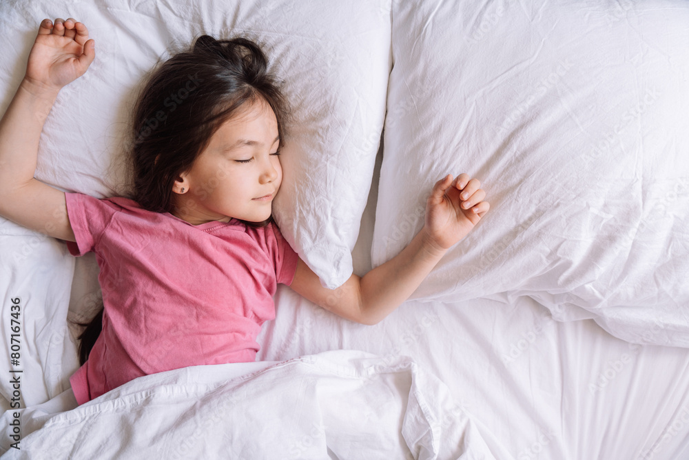 Little girl in pink pajamas sleeps in a white bed. Little girl in pink pajamas sleeps in a white bed.