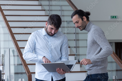 Vászonkép deux jeune hommes d'affaire ou employés de bureau discutent debout dans les locaux de leur entreprise
