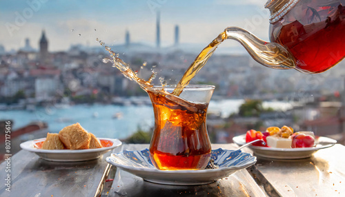Advertisement Traditional Turkish cup of tea with teapot and splash of tea against city view, Istanbul skyline