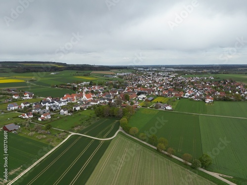 Drohnenaufnahme von einem idyllischen Dorf im Alb-Donau-Kreis mit großem Industriegebiet im Hintergrund