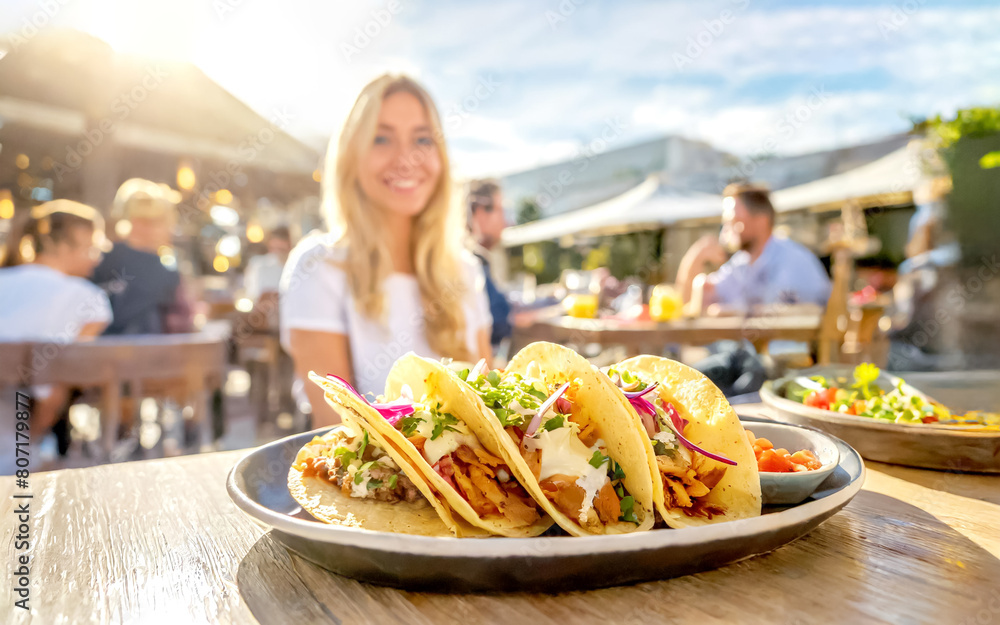 Tacos mit Füllung, im Hintergrund ein Restaurant mit Gästen Tacos mit Füllung, im Hintergrund ein Restaurant mit Gästen