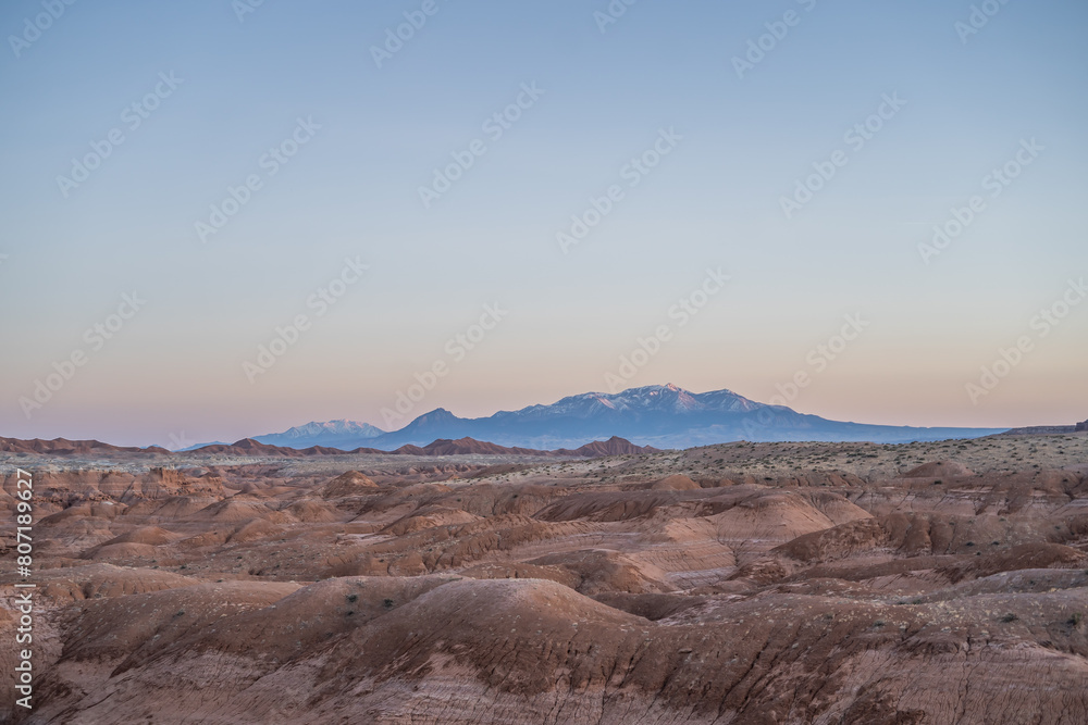Fototapeta premium Gorgeous Desert Hills in Goblin Valley Utah Snow Capped Mountains Sunset