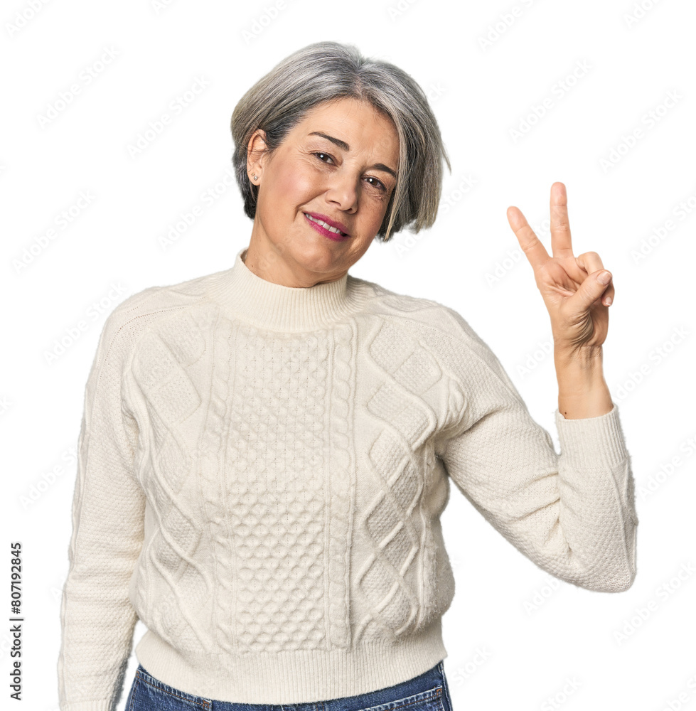 Caucasian mid-age female on studio background joyful and carefree showing a peace symbol with fingers. Caucasian mid-age female on studio background joyful and carefree showing a peace symbol with fingers.