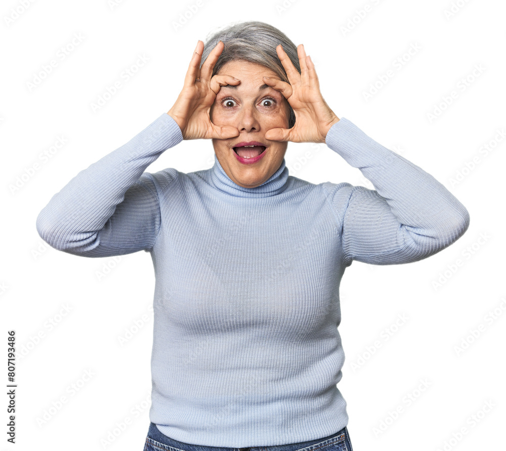 Caucasian mid-age female on studio background keeping eyes opened to find a success opportunity.