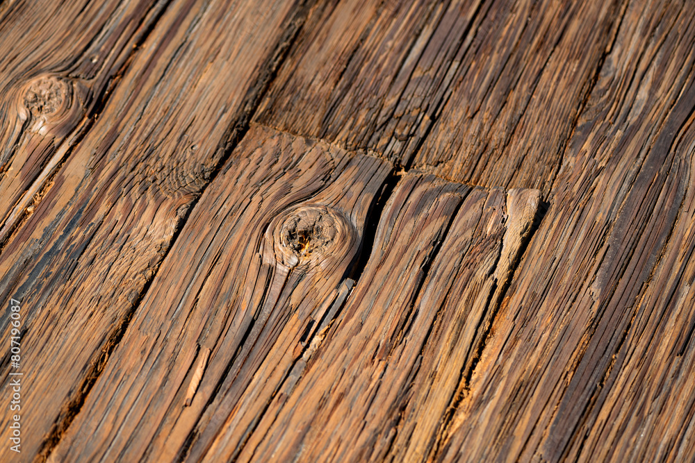 Obraz premium Worn, weathered wooden planks on a wooden pier in Santa Barbara, California (USA). Diagonal old wooden plank surface after long use in different shades of brown. Macro structure with knotholes.