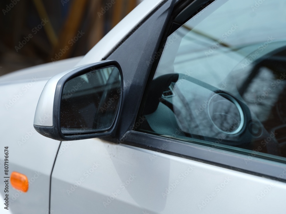 A close-up shot of the left side mirror of a silver car. A close-up shot of the left side mirror of a silver car.