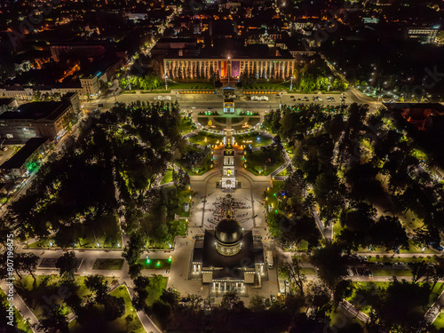 Drone aerial view of a crowd of people at an Easter night service near the cathedral with Chisinau's nightscape in the background, featuring the bell tower, the Triumph Arch, the Government building, 