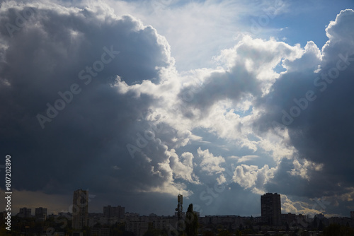 Sunlight falls on the city through dark clouds, light breaks through the clouds, weather change, after the past storm