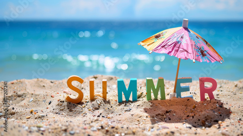 texte "SUMMER" écrit avec des lettres en bois colorés sur la plage sous un parasol de cocktail