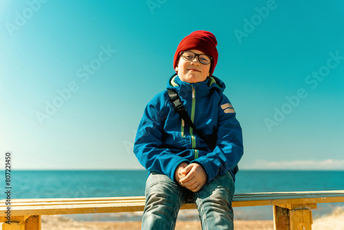 A boy is sitting on a bench on a spring beac photo