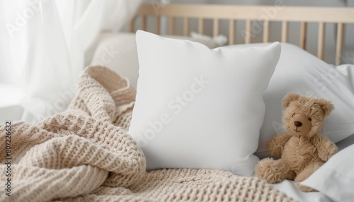 Mockup of a square baby pillow white nursery cushion on blanket with toy bear photo