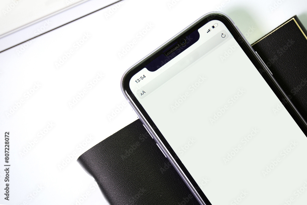 phone with black textured notebook on a white background. View from above phone with black textured notebook on a white background. View from above