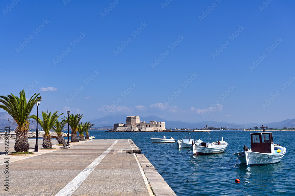 Small fishing boats and Bourtzi fortress in Nafplio, Peloponnese, Greece