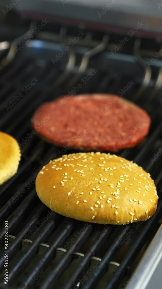 Fresh buns and raw cutlet are grilled on a barbeque. Selective focus on frying process. Vertical video Fresh buns and raw cutlet are grilled on a barbeque. Selective focus on frying process. Vertical video