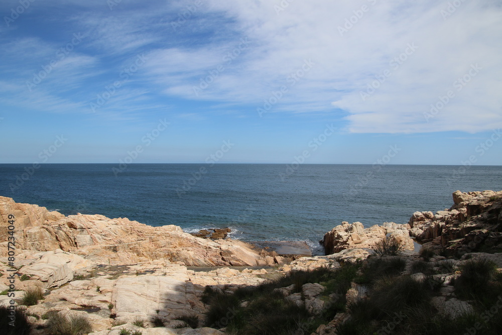 Natural and small coves of the Costa Brava with boats in the background and the blue sky with clouds and blue water. A beautiful place for vacations. Natural and small coves of the Costa Brava with boats in the background and the blue sky with clouds and blue water. A beautiful place for vacations.