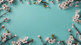 Beautiful Turquoise blue background with spring cherry blossom branches, top view, flat lay, frame. Creative springtime layout