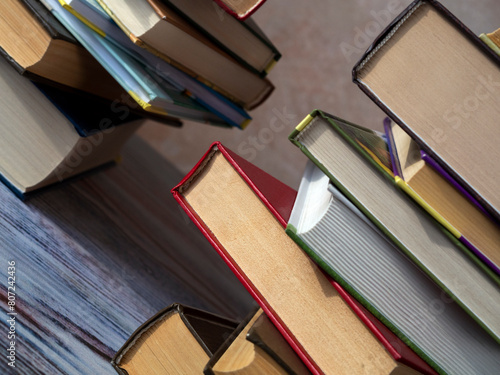 Stacks of books on the table at an angle to the background. Close-up. Books lie on top of each other with an offset. Concept of learning, reading, education.