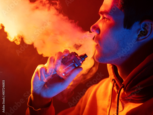 A man exhales steam from an electonic cigarette. Pod in hand photo