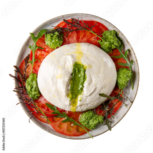 Tomato salad with burrata cheese and green pesto on gray plate isolated on white background. Top view.