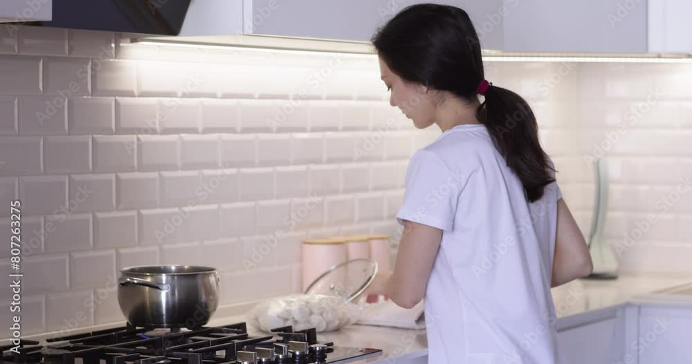 woman cooking dumpling in boiling water in the kitchen woman cooking dumpling in boiling water in the kitchen