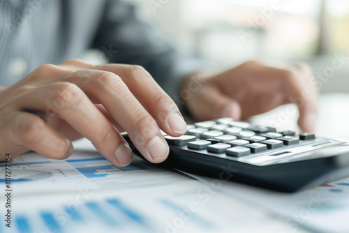 Professional Calculating Financial Data on Calculator. Close-up of a professional's hands using a calculator over financial charts, analyzing and calculating business data.