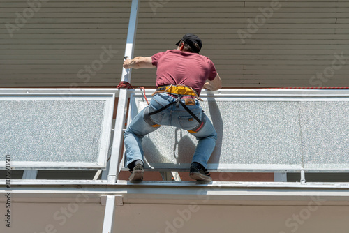 Worker paints the balcony in the house at height, industrial climbing, painting of tall buildings and objects