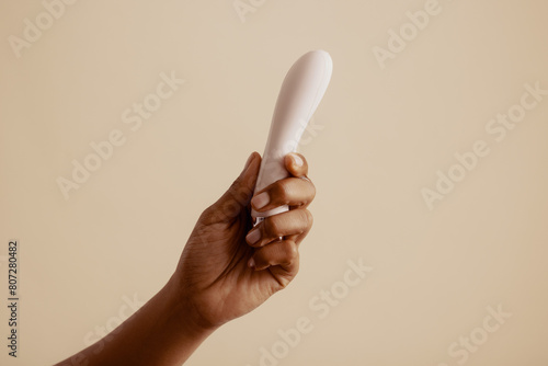 Female hand holds lubricated vibrator for solo pleasure photo