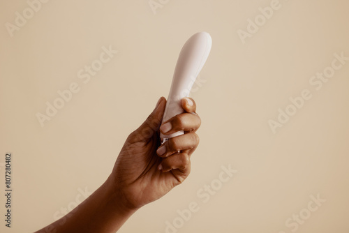Female hand holds lubricated vibrator for solo pleasure