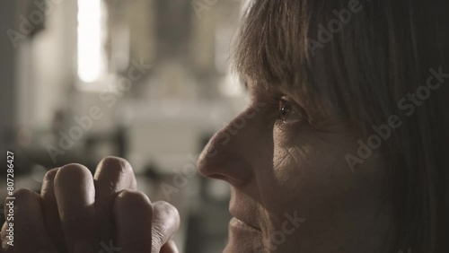 Mid adult woman praying with clasped hands close up side view. Caucasian religious person with closed eyes and clenched fists during prayer. Christianity worship concept photo