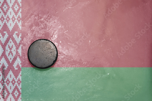 old hockey puck is on the ice with national flag of belarus .