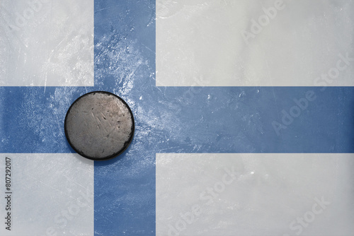 old hockey puck is on the ice with national flag of finland .