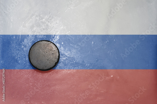 old hockey puck is on the ice with national flag of russia . photo
