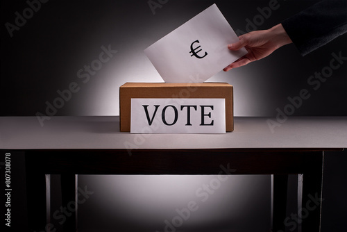 Hand puts ballot paper with euro sign into voting box