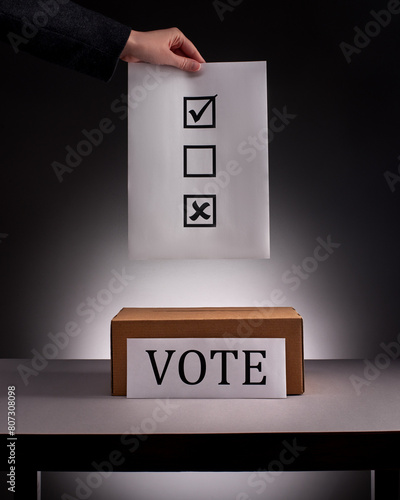 Рand in business suit holding ballot paper over voting box