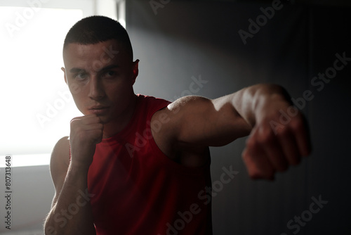 Young serious man with clenched fists concentrating attention on rival or punching bag while practicing basic kicks and defense techniques © pressmaster