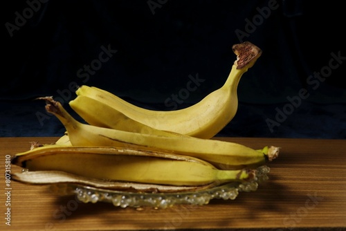 In a glass bowl there is a ripe banana and a banana peel.